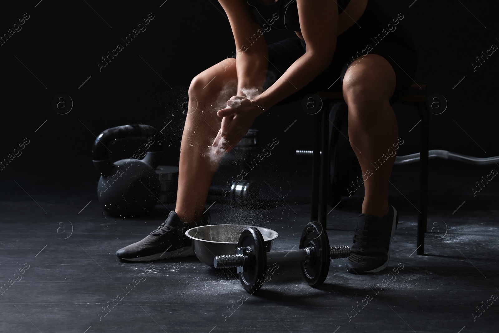 Photo of Woman applying talcum powder onto hands before training in gym, closeup