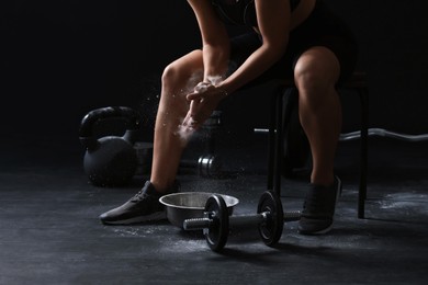 Photo of Woman applying talcum powder onto hands before training in gym, closeup