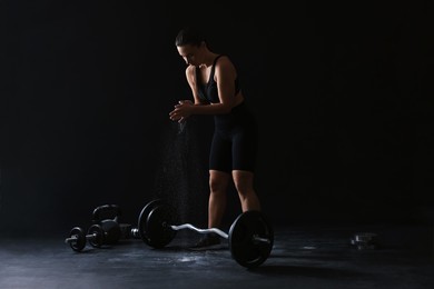 Photo of Woman applying talcum powder onto hands before training on black background