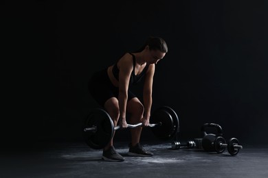 Photo of Woman training with barbell against black background