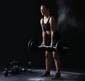 Photo of Woman training with barbell against black background