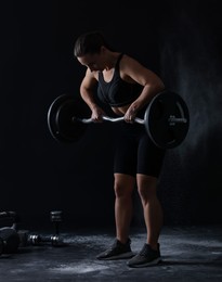 Photo of Woman training with barbell against black background