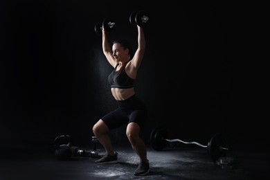 Woman training with barbells on black background