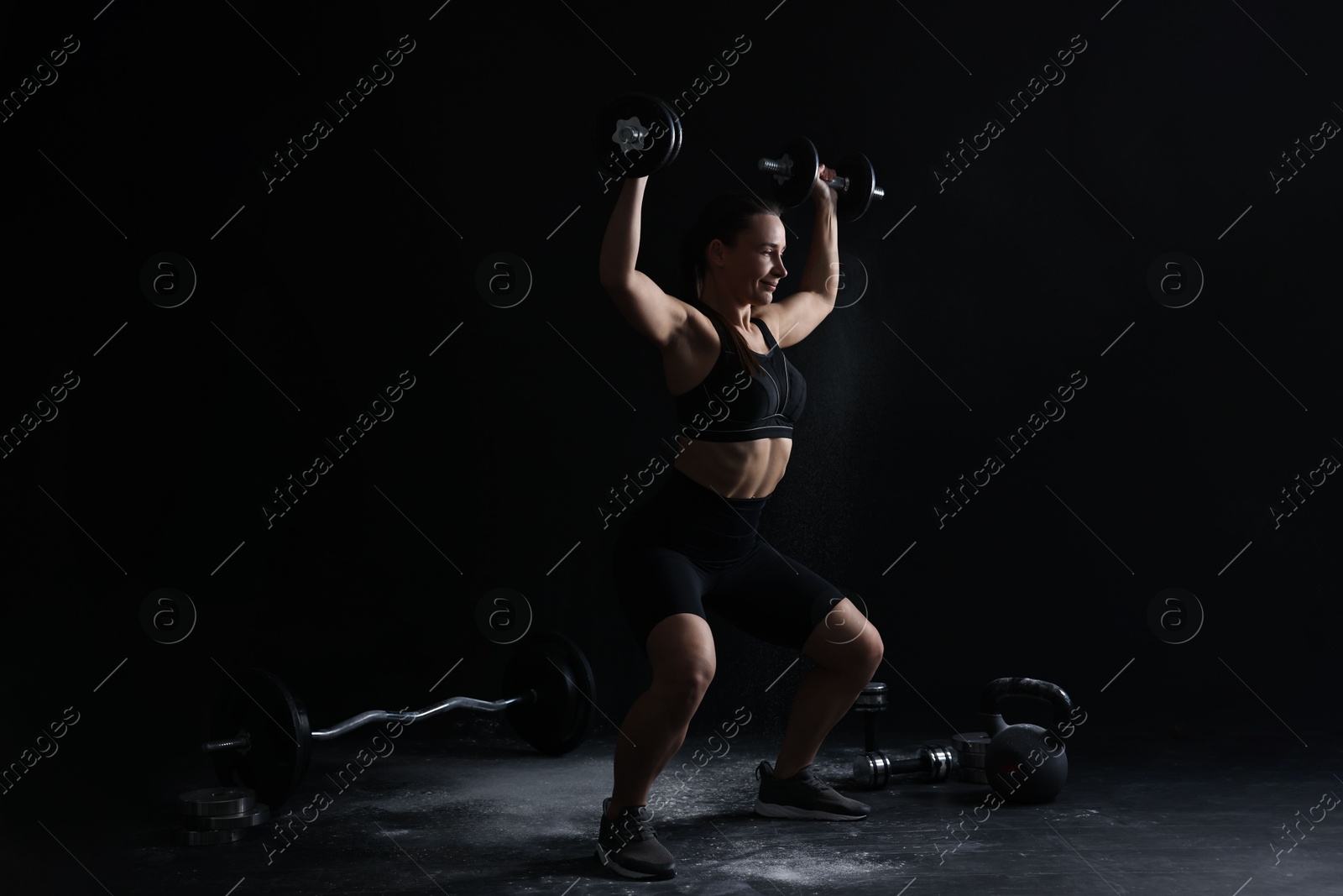 Photo of Woman training with barbells on black background