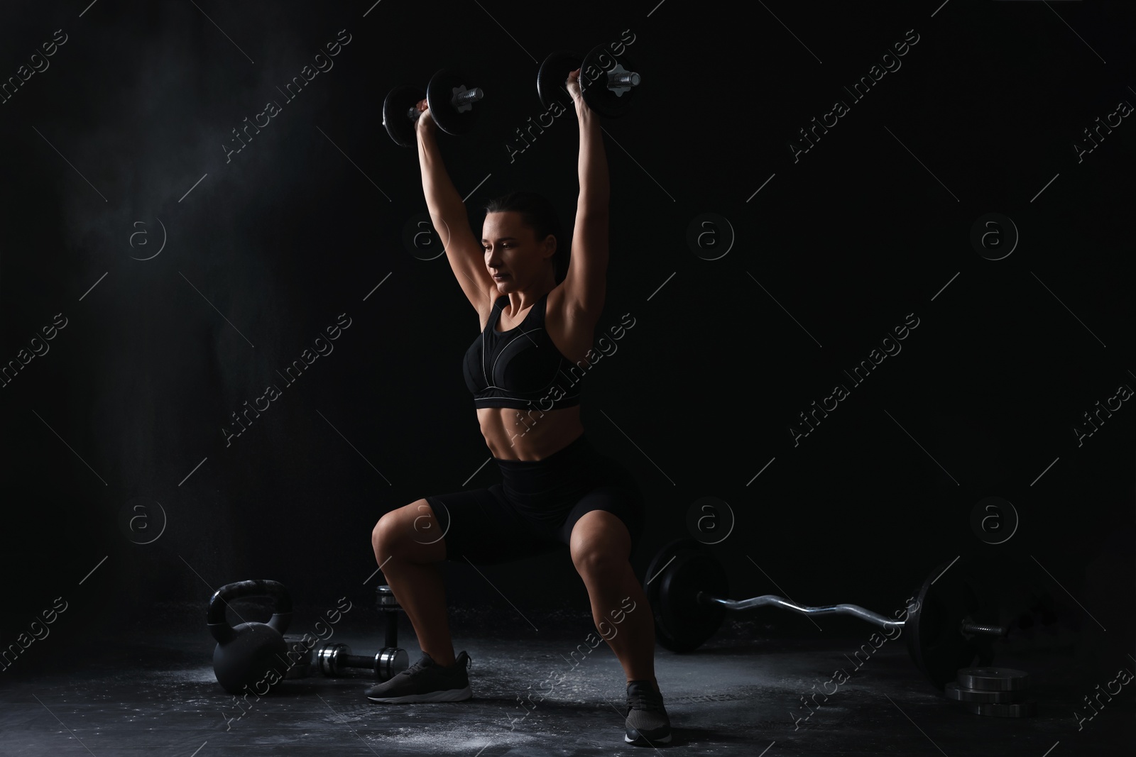 Photo of Woman training with barbells on black background