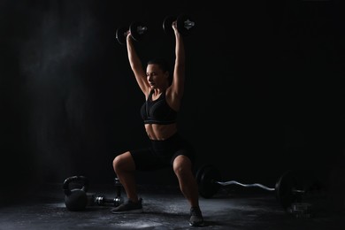 Woman training with barbells on black background