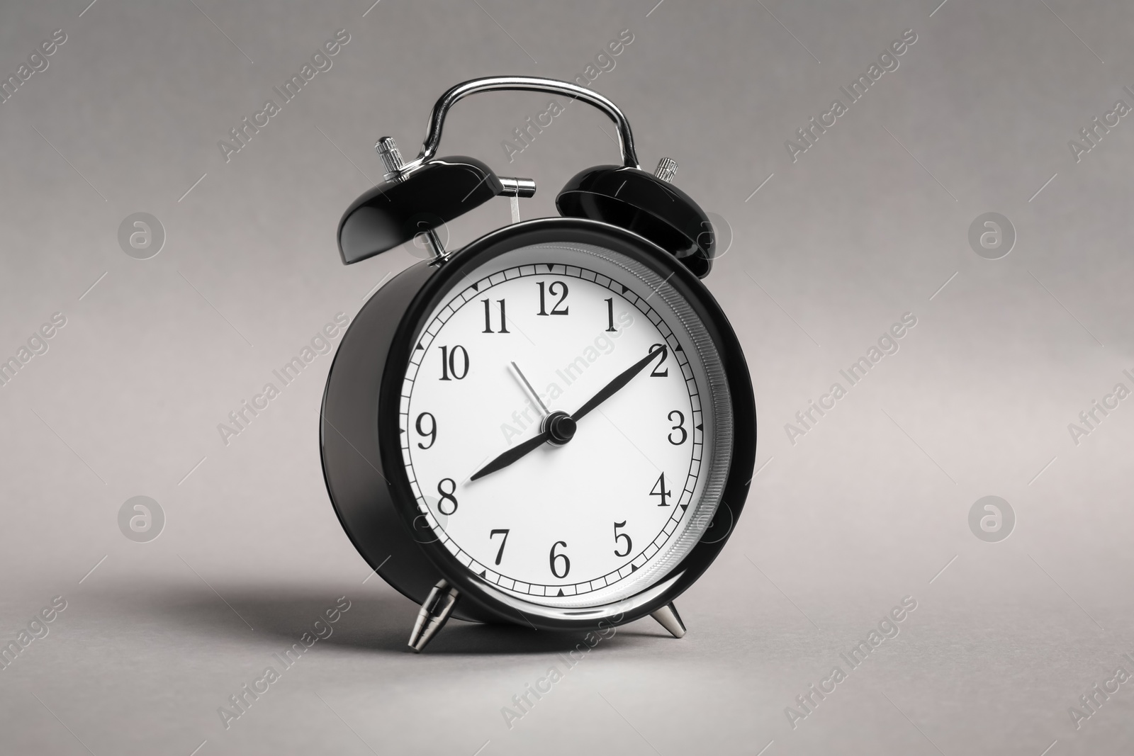 Photo of One black alarm clock on grey background