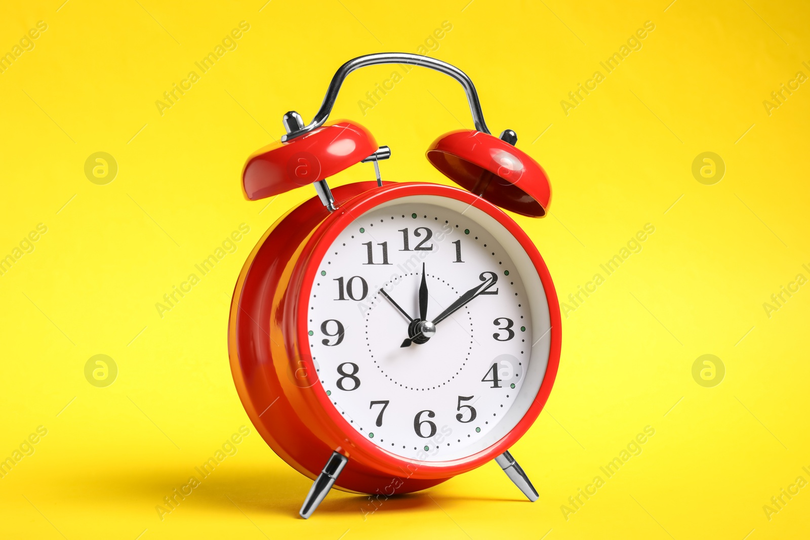 One red alarm clock on yellow background Photo of One red alarm clock on yellow background