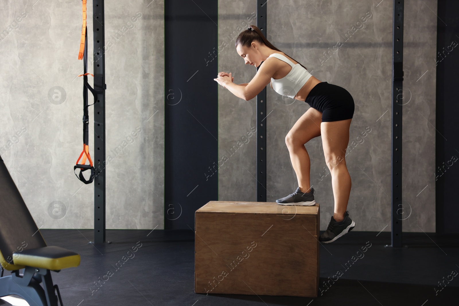 Photo of Sportswoman exercising on cube during crossfit workout in gym. Space for text