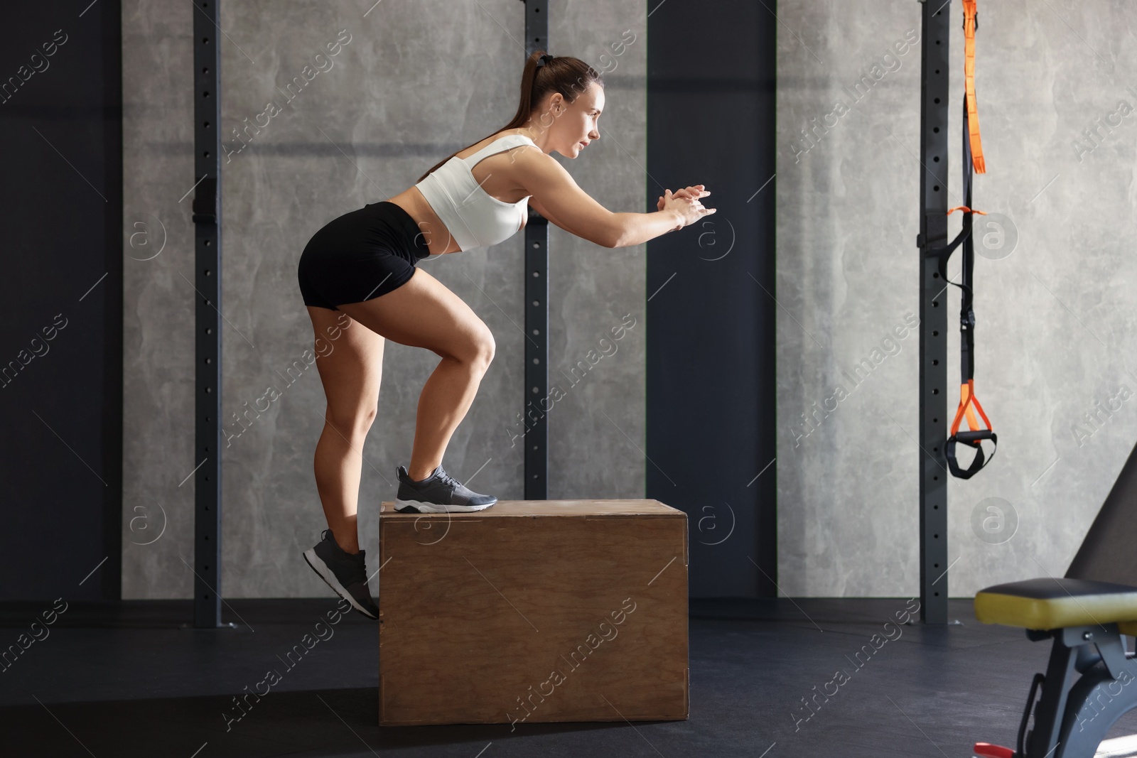 Photo of Sportswoman exercising on cube during crossfit workout in gym