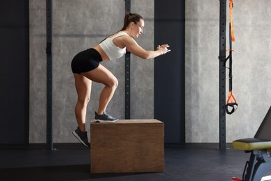 Photo of Sportswoman exercising on cube during crossfit workout in gym