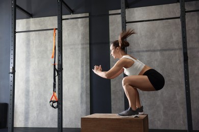 Photo of Sportswoman doing box jumping during crossfit workout in gym. Space for text