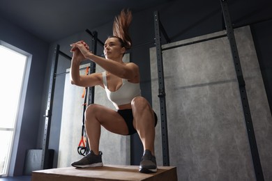 Photo of Sportswoman doing box jumping during crossfit workout in gym. Space for text