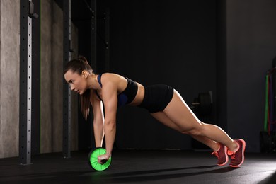 Photo of Sportswoman exercising with ab wheel during crossfit workout in gym