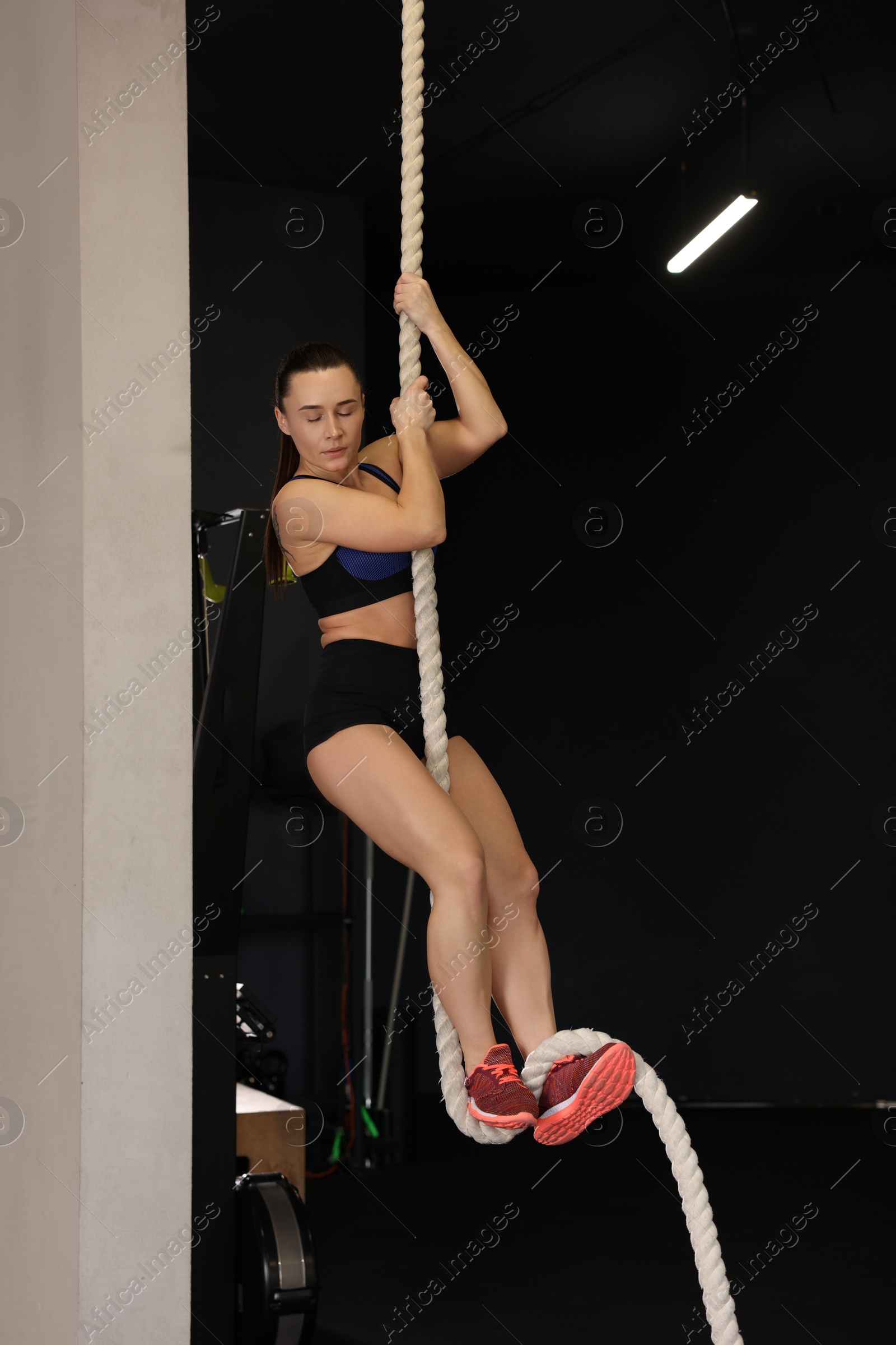 Photo of Sportswoman doing rope climbing during crossfit workout in gym