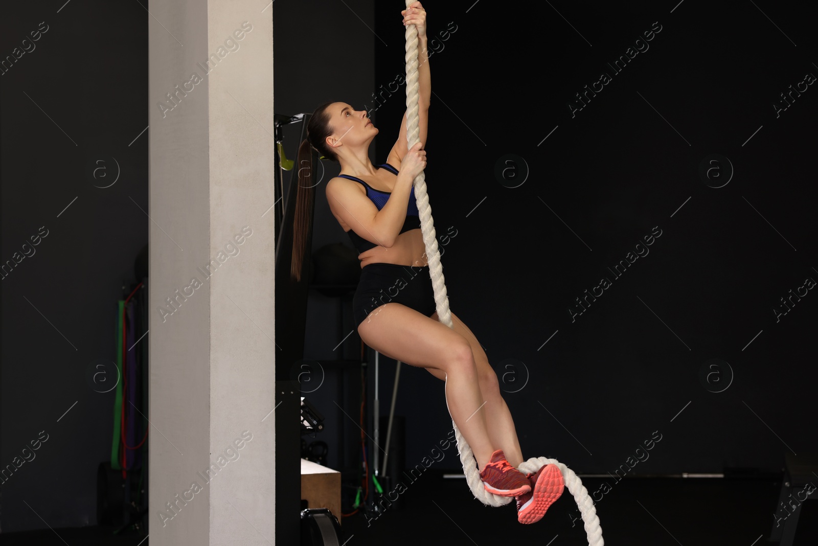 Photo of Sportswoman doing rope climbing during crossfit workout in gym. Space for text