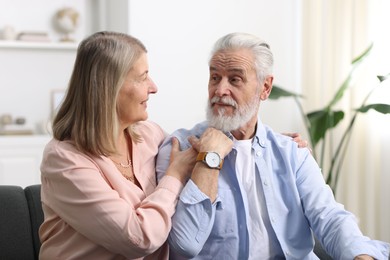 Cute elderly couple looking at each other at home