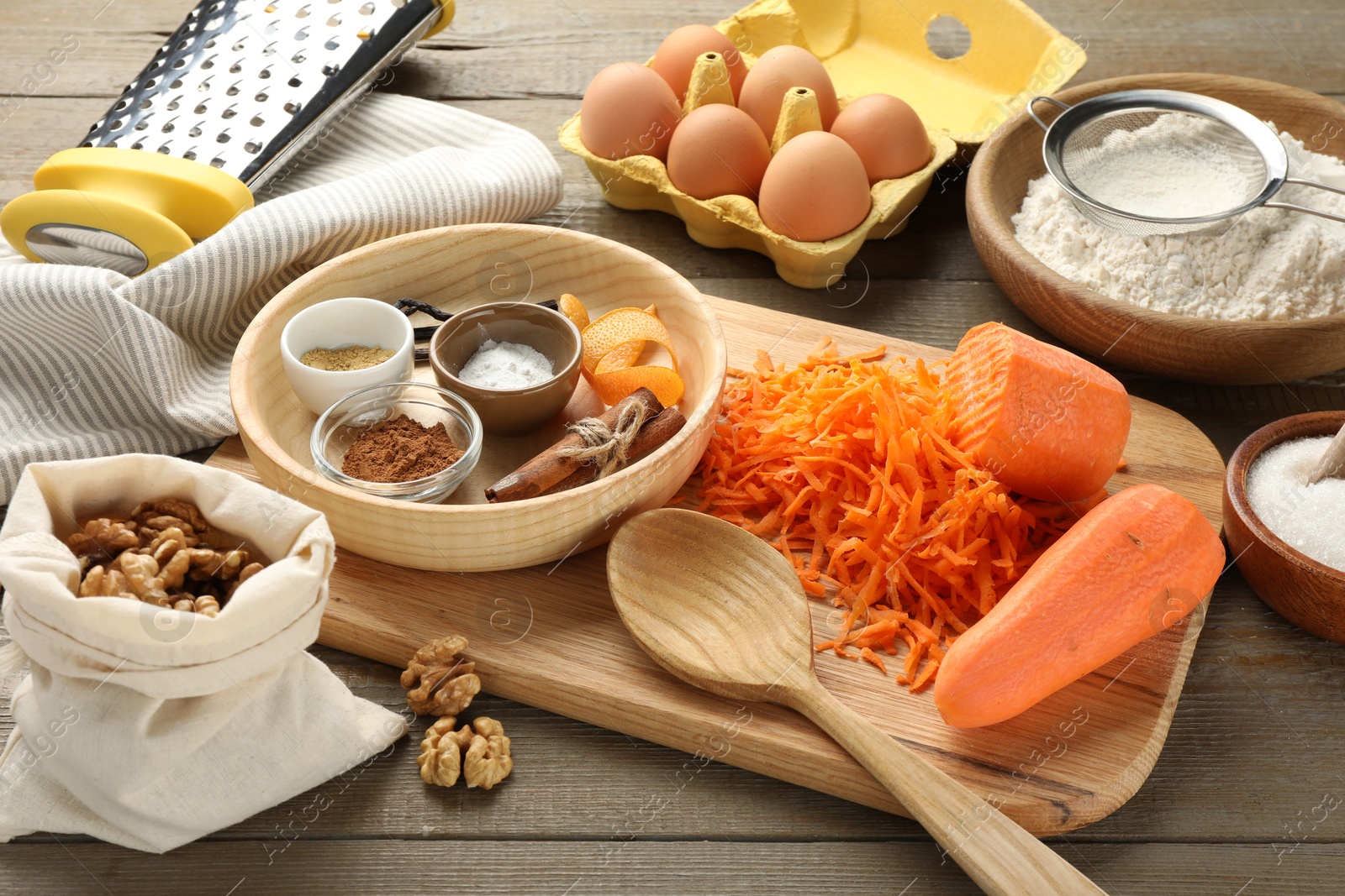 Photo of Different ingredients for making carrot cake and kitchenware on wooden table, closeup