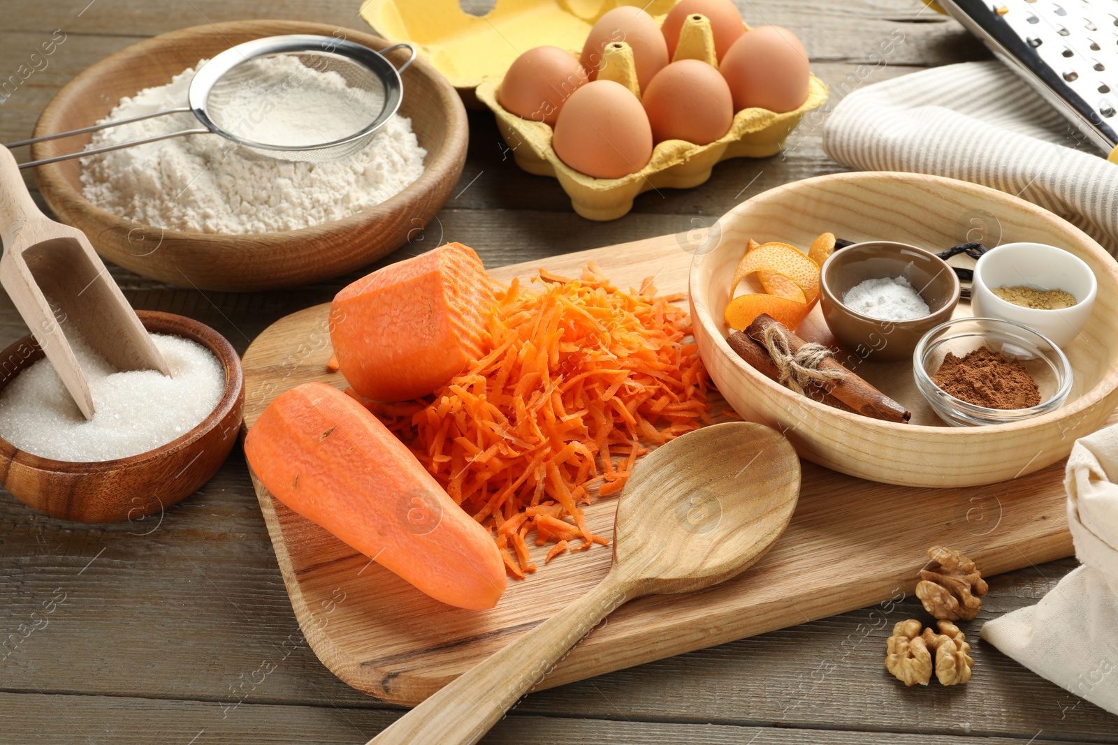 Photo of Different ingredients for making carrot cake and kitchenware on wooden table, closeup