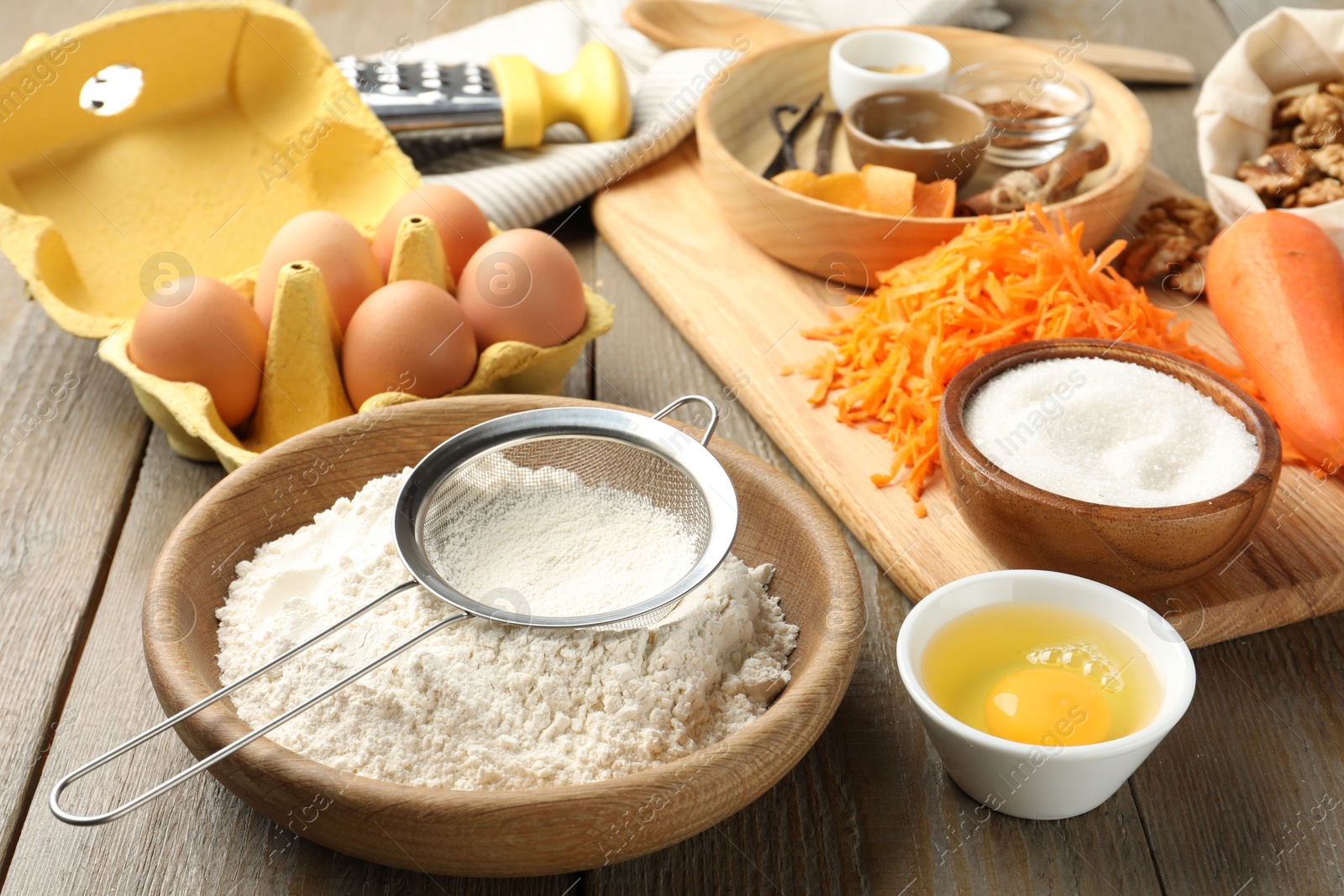 Photo of Different ingredients for making carrot cake and kitchenware on wooden table, closeup