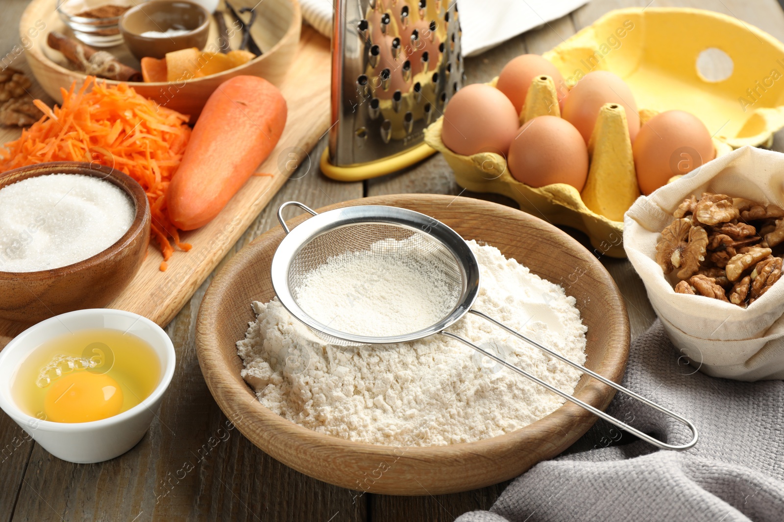 Photo of Different ingredients for making carrot cake and kitchenware on wooden table, closeup