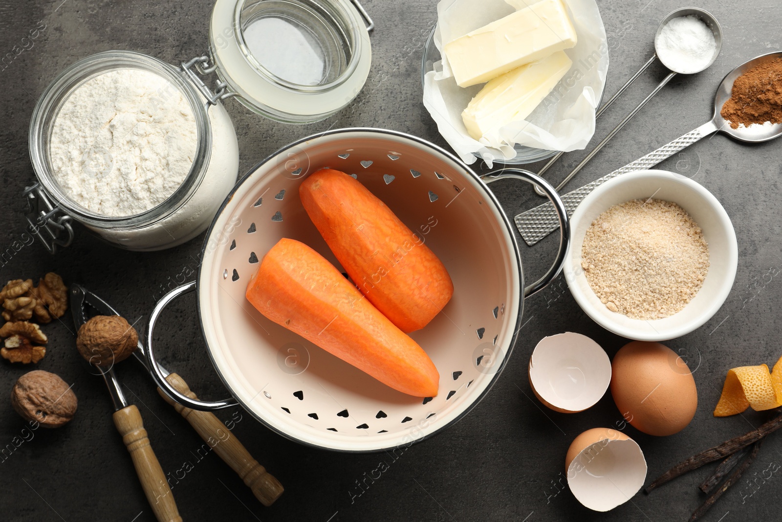 Photo of Different ingredients for making carrot cake and kitchenware on dark textured table, flat lay