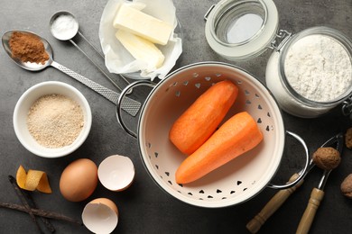 Photo of Different ingredients for making carrot cake and kitchenware on dark textured table, flat lay