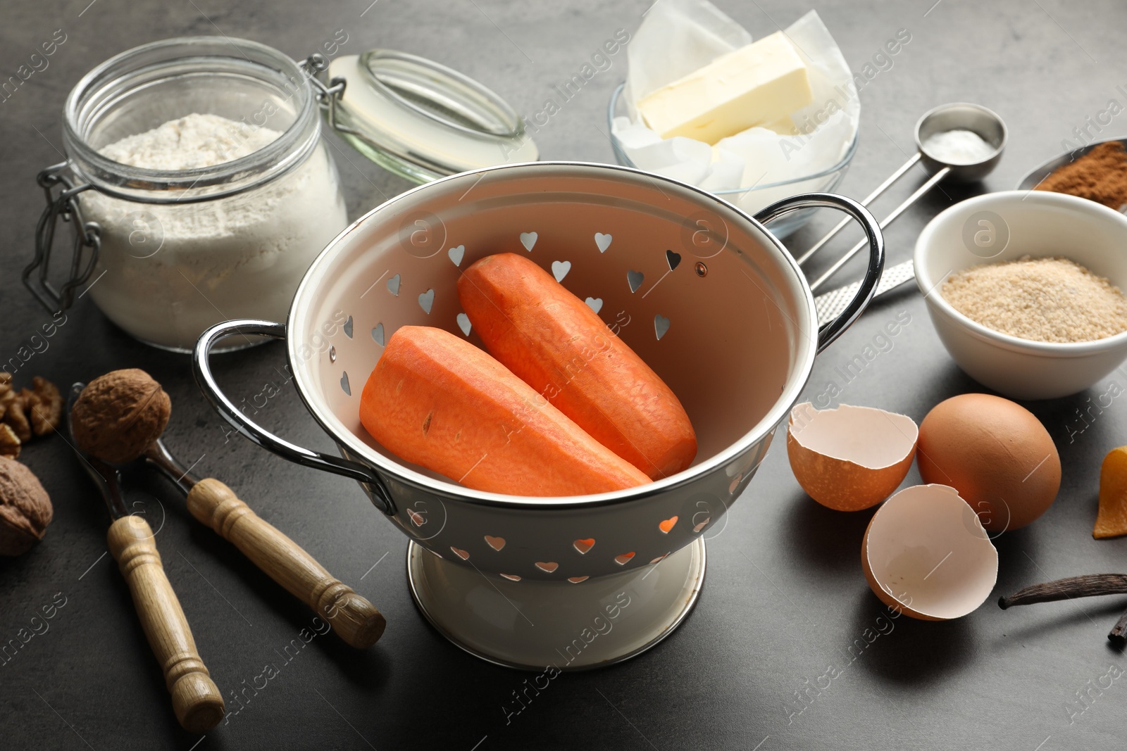 Photo of Different ingredients for making carrot cake and kitchenware on dark textured table, closeup