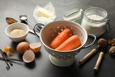 Photo of Different ingredients for making carrot cake and kitchenware on dark textured table, closeup