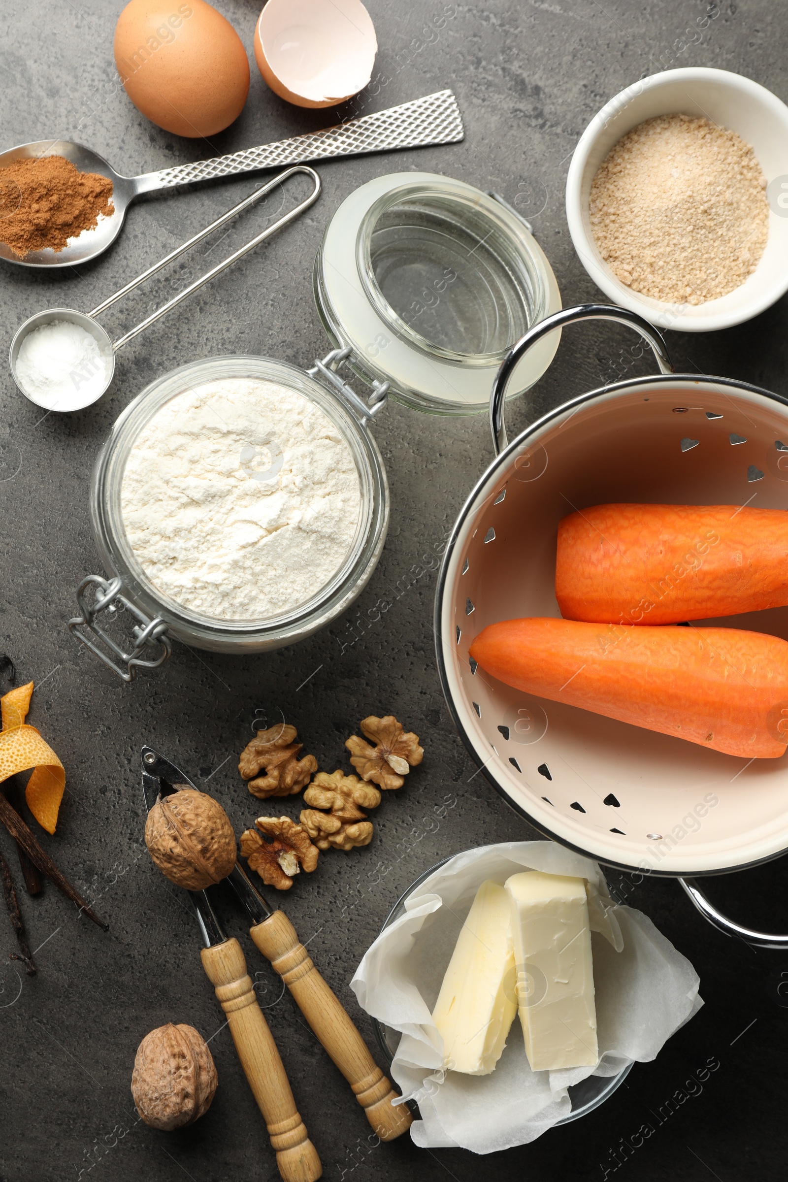 Photo of Different ingredients for making carrot cake and kitchenware on dark textured table, flat lay