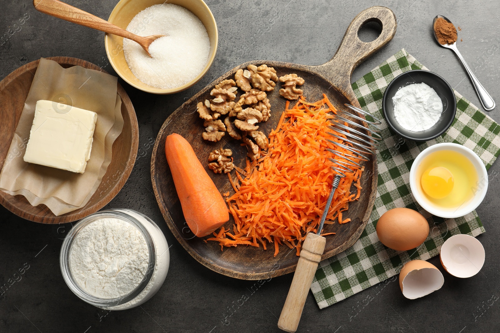 Photo of Different ingredients for making carrot cake and kitchenware on dark textured table, flat lay