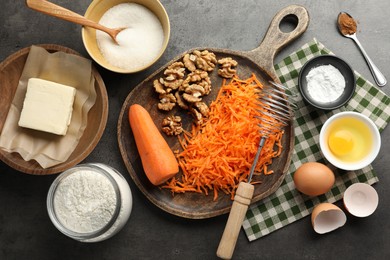 Photo of Different ingredients for making carrot cake and kitchenware on dark textured table, flat lay