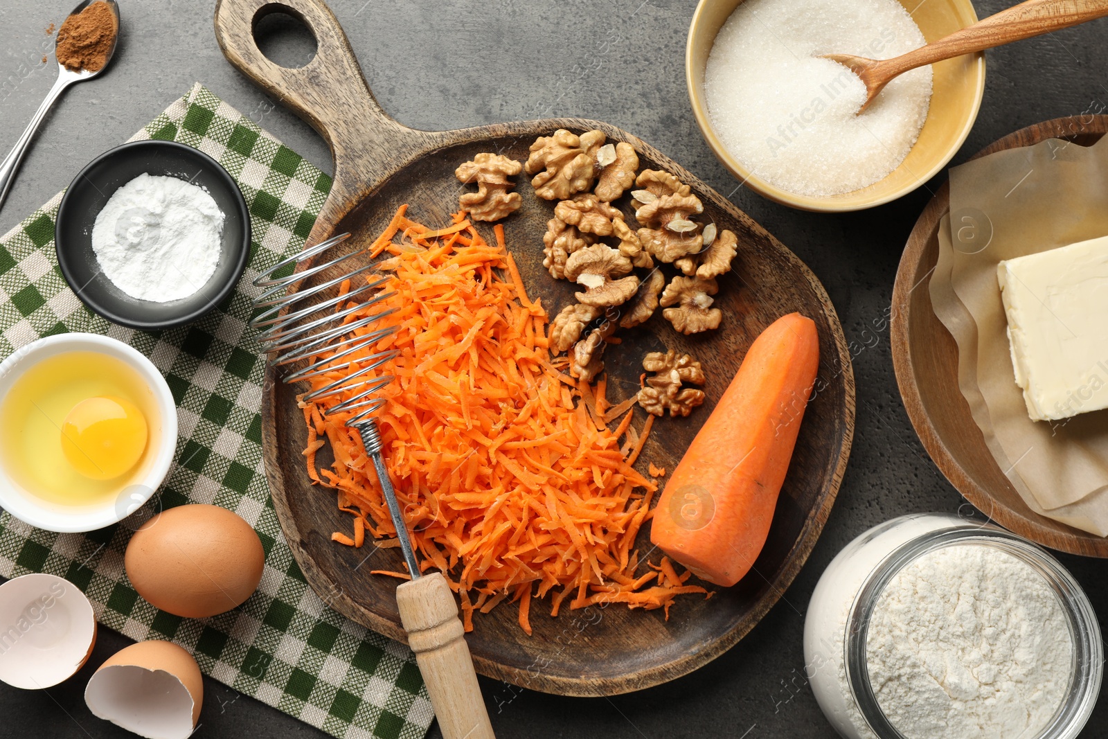 Photo of Different ingredients for making carrot cake and kitchenware on dark textured table, flat lay