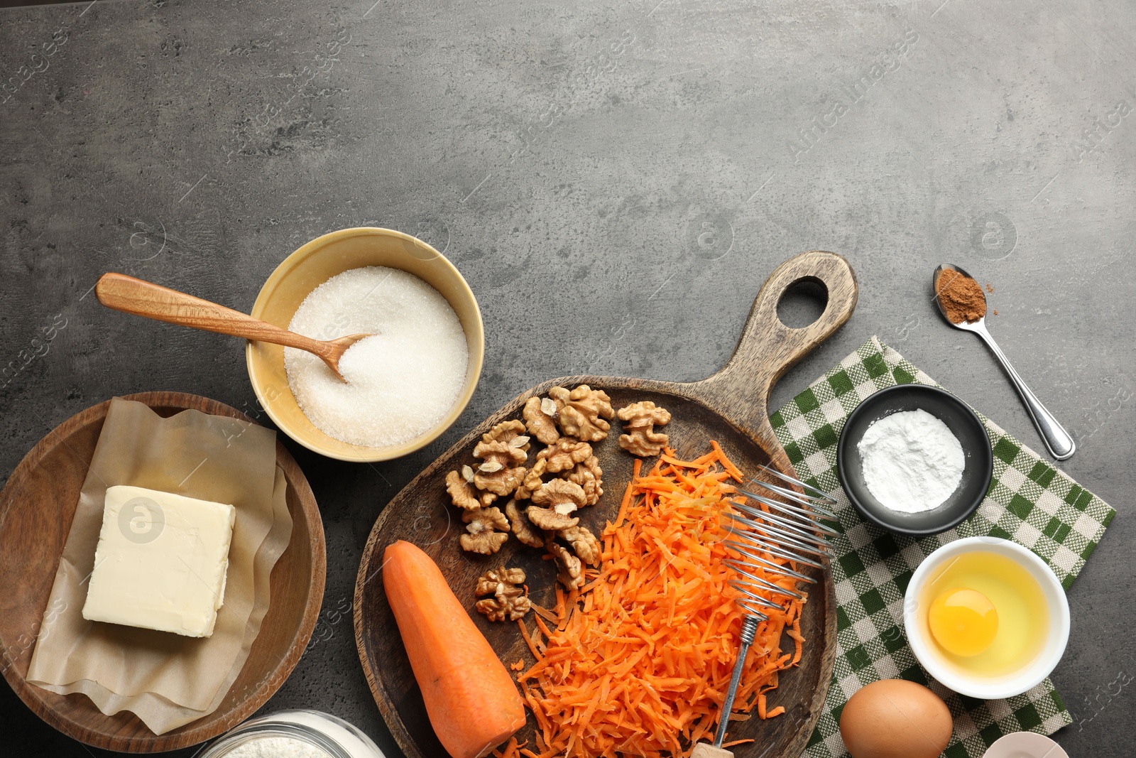 Photo of Different ingredients for making carrot cake and kitchenware on dark textured table, flat lay. Space for text