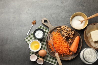 Photo of Different ingredients for making carrot cake and kitchenware on dark textured table, flat lay. Space for text