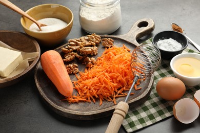 Photo of Different ingredients for making carrot cake and whisk on dark textured table, closeup