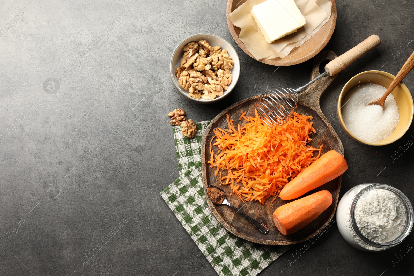 Photo of Different ingredients for making carrot cake and kitchenware on dark textured table, flat lay. Space for text