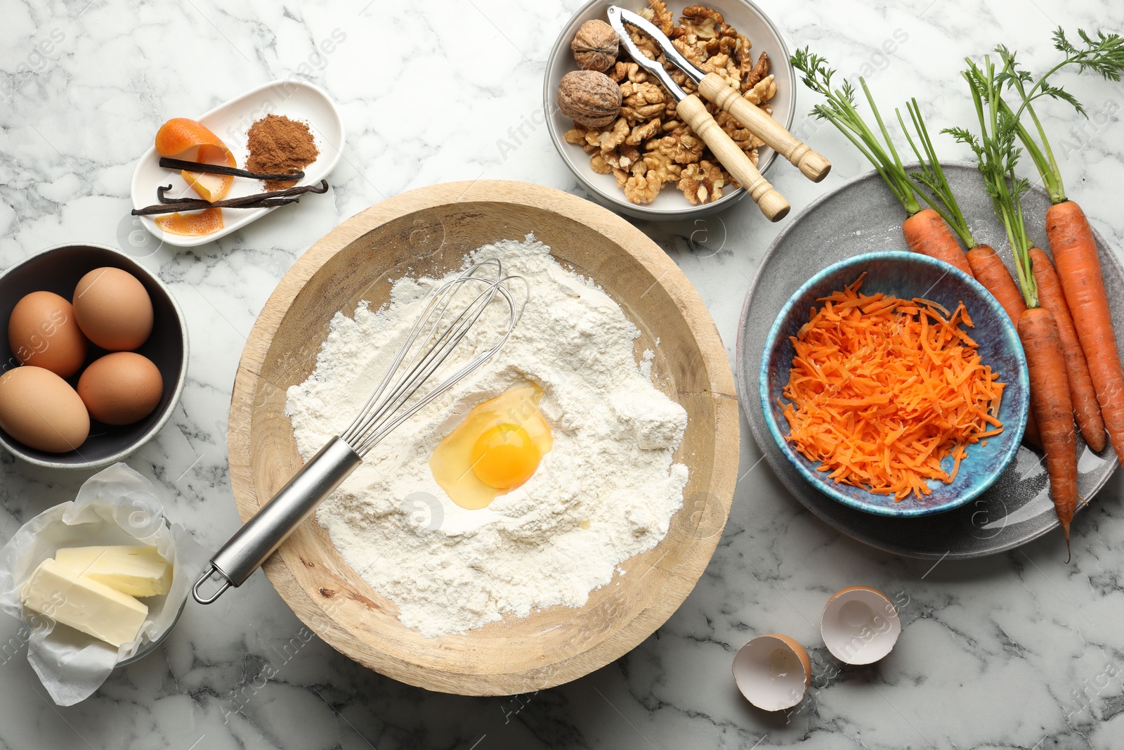 Photo of Making carrot cake. Different ingredients for dough and kitchenware on white marble table, flat lay