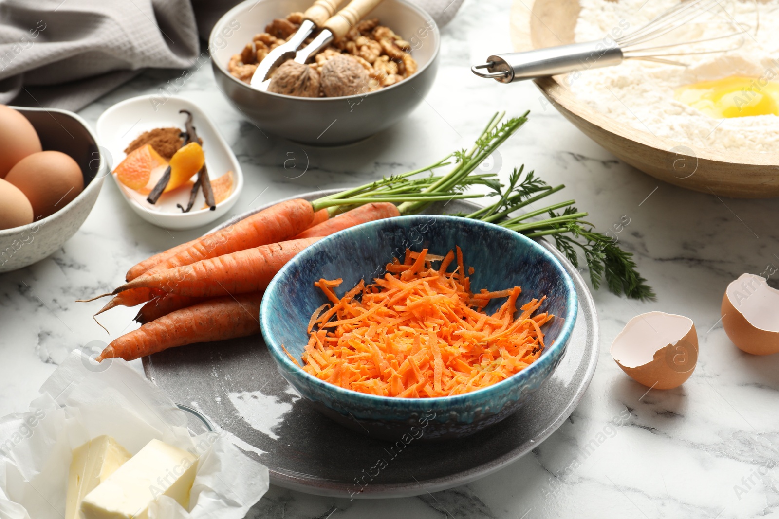 Photo of Making carrot cake. Vegetable and other ingredients on white marble table, closeup