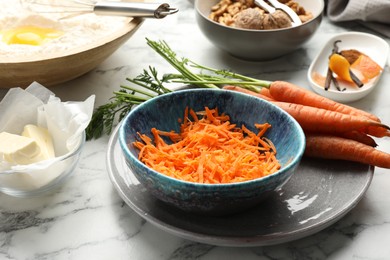 Photo of Making carrot cake. Vegetable and other ingredients on white marble table, closeup