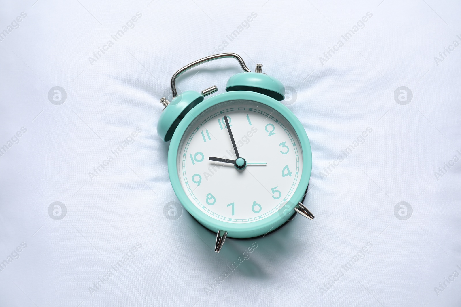 Photo of Alarm clock on pillow, top view. Time for sleeping