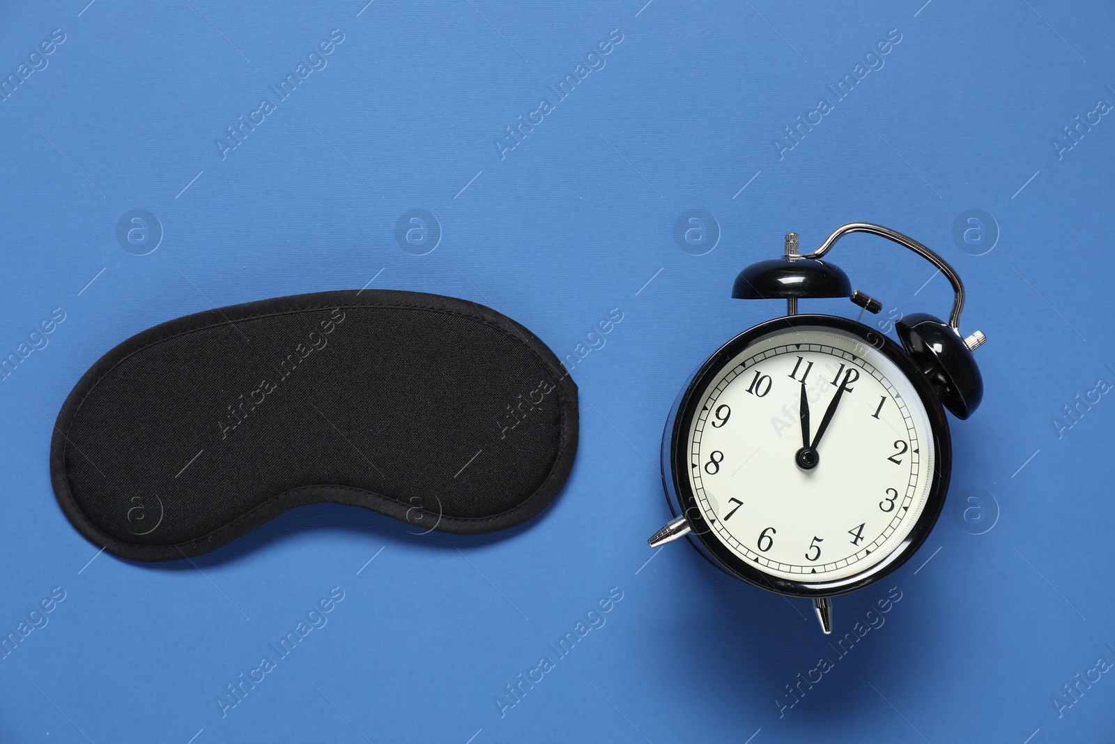 Photo of Alarm clock and sleep mask on blue background, flat lay. Time for sleeping