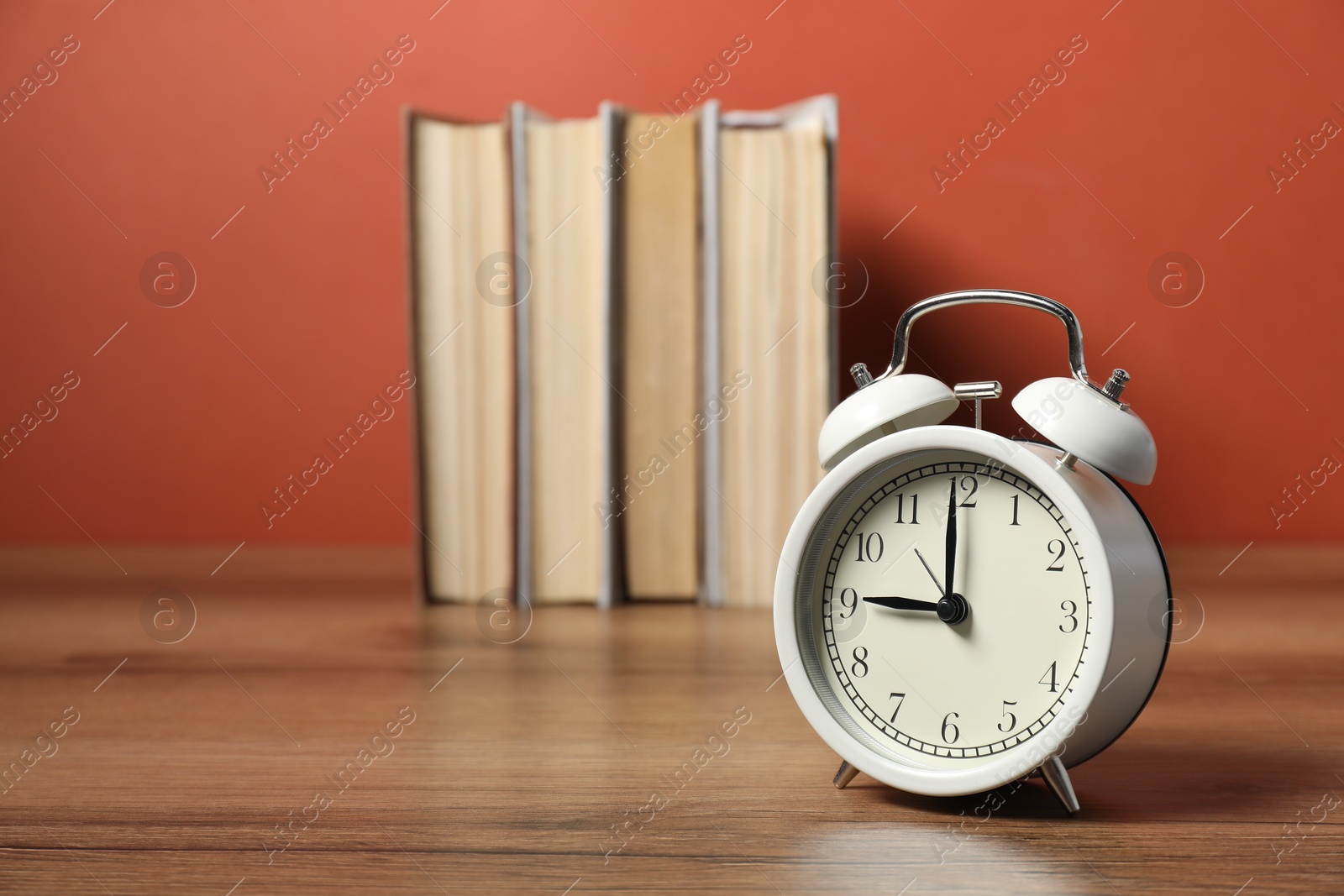 Photo of Alarm clock and books on wooden table, space for text. Time for knowledge