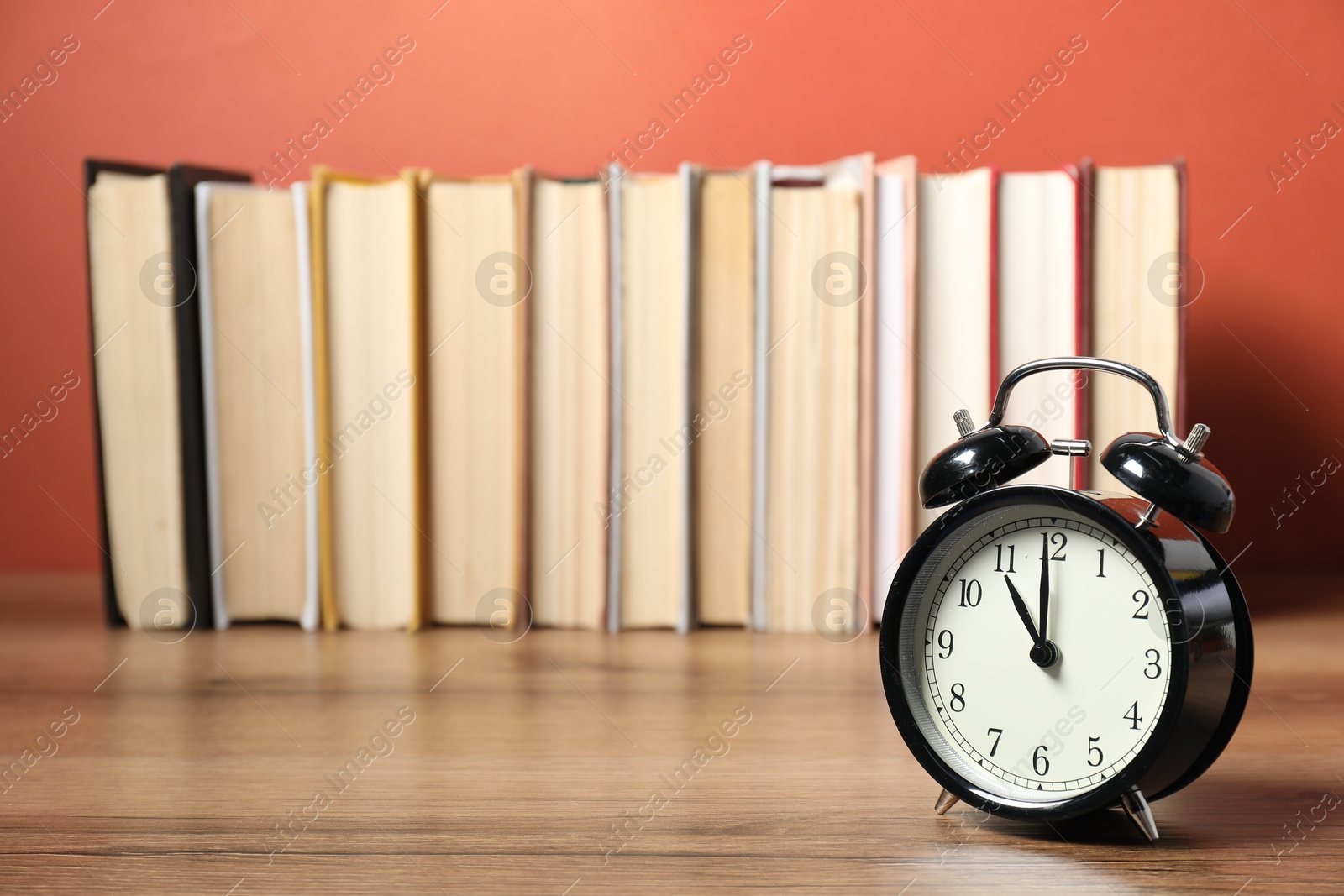 Photo of Alarm clock and books on wooden table, space for text. Time for knowledge