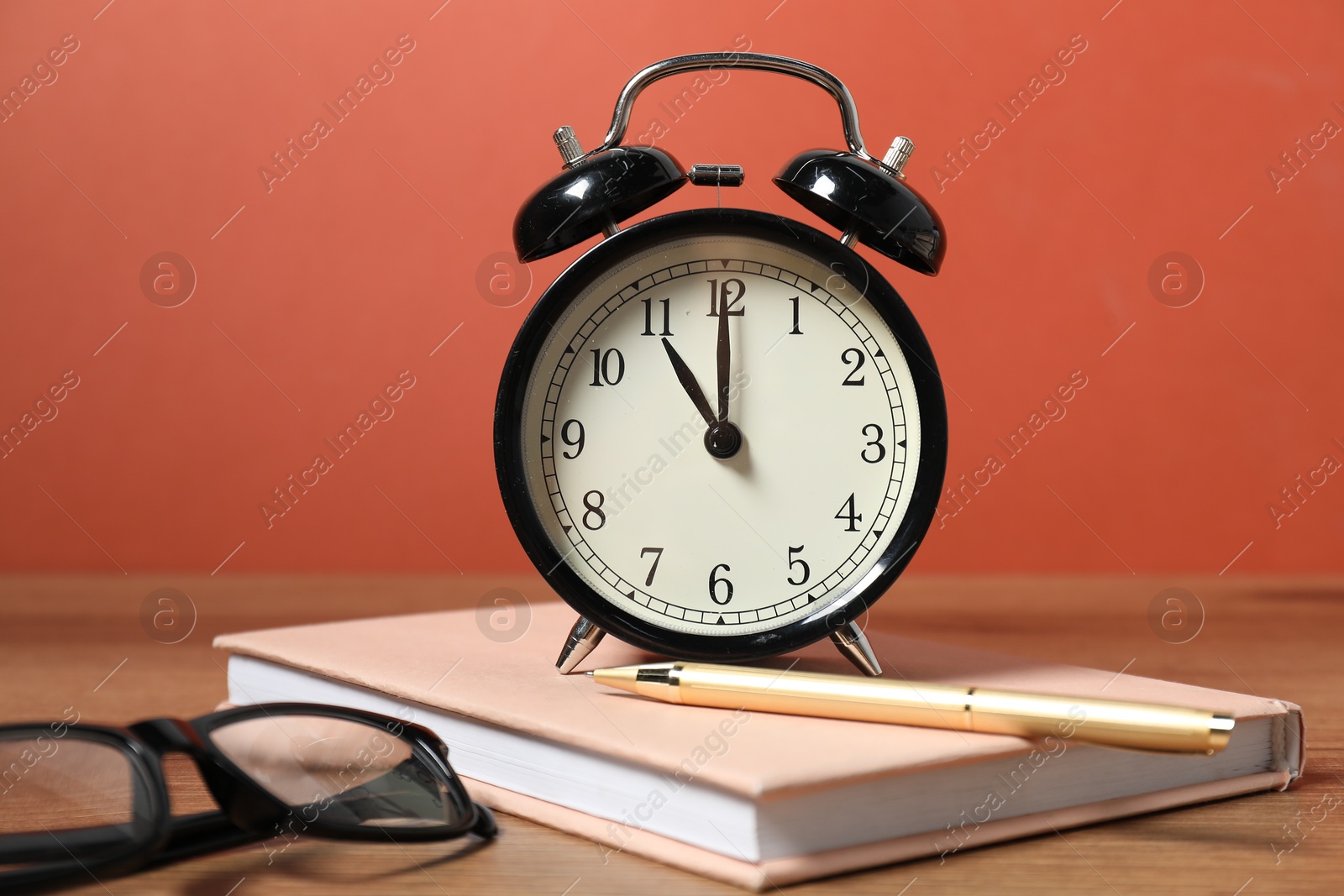 Photo of Alarm clock, stationery and glasses on wooden table. Time for knowledge