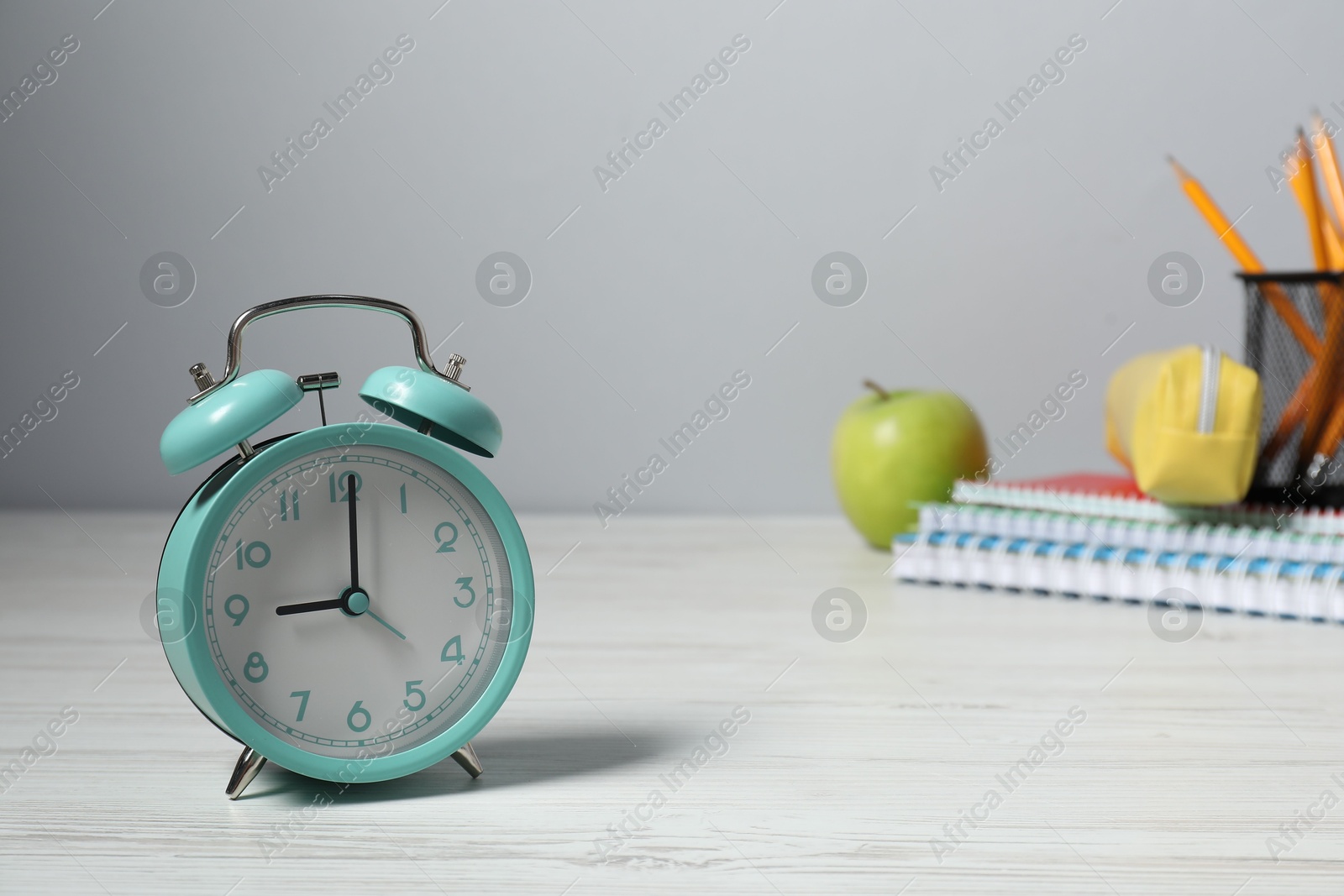 Photo of Alarm clock, stationery and apple on white wooden table. Time for knowledge