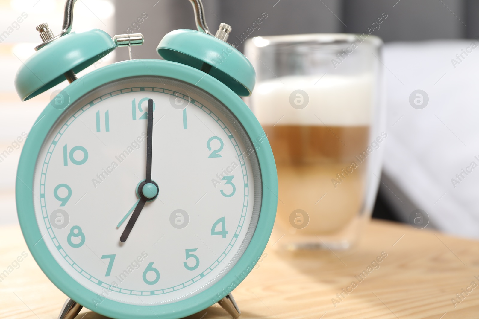 Photo of Alarm clock and coffee on nightstand near bed, closeup