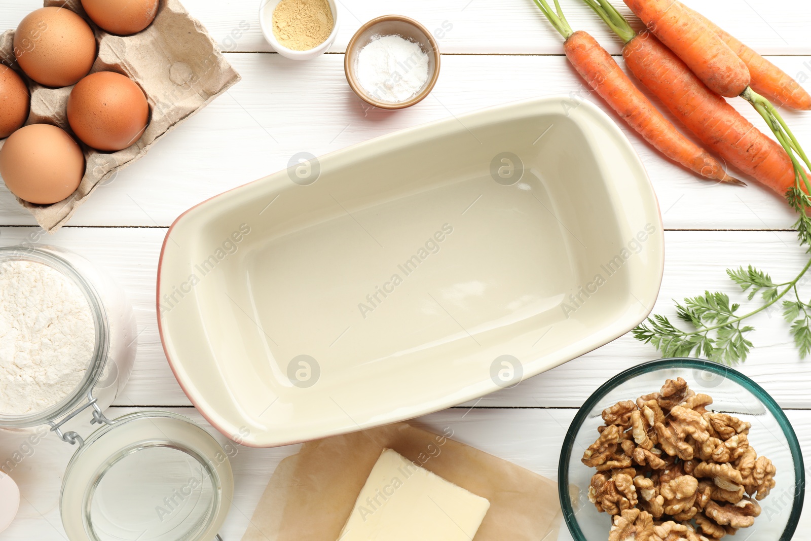 Photo of Different ingredients for making carrot cake and baking dish on white wooden table, flat lay