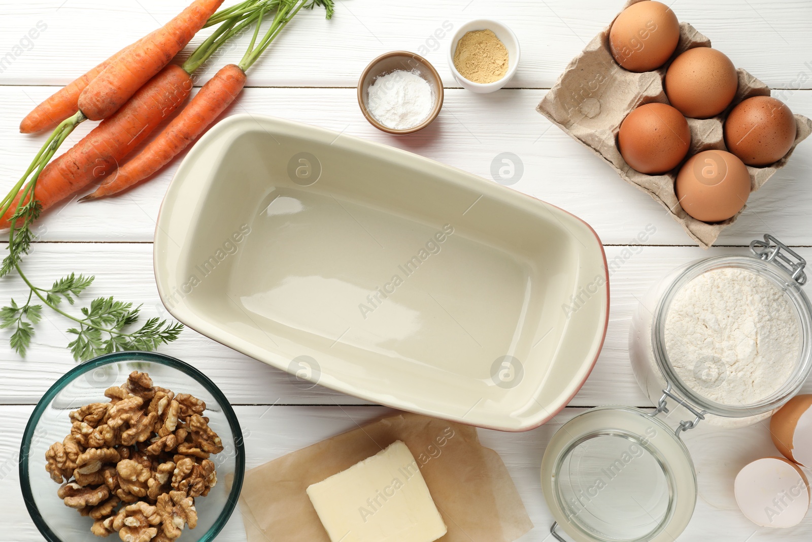 Photo of Different ingredients for making carrot cake and baking dish on white wooden table, flat lay