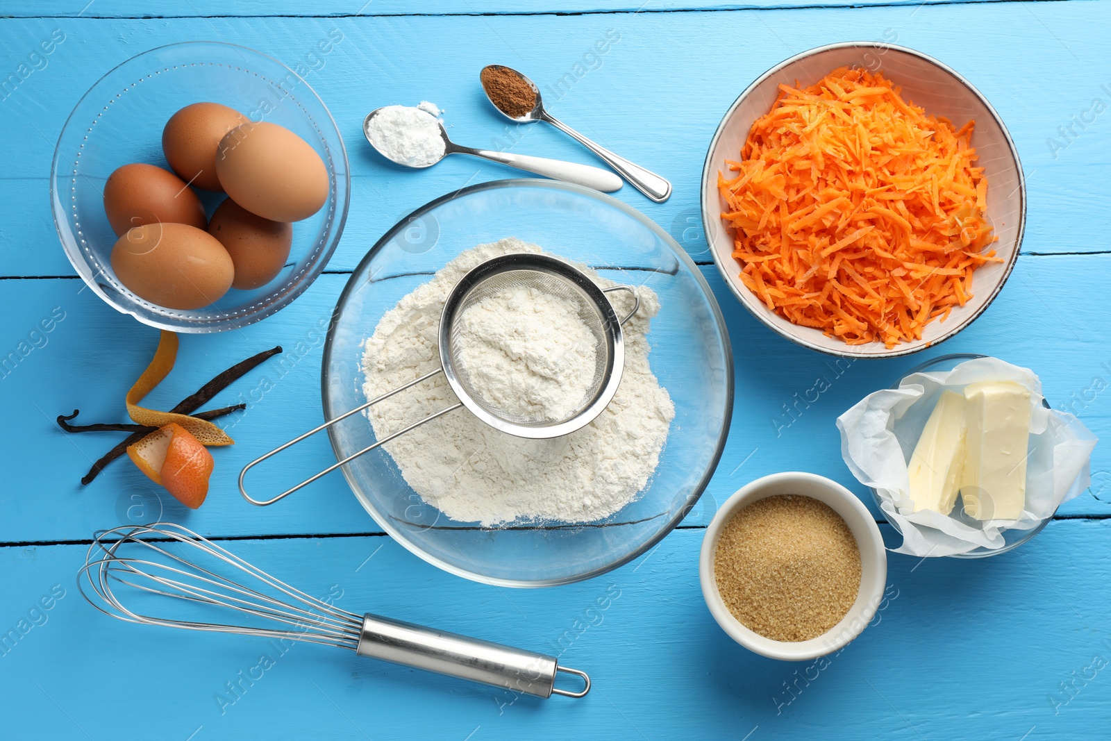 Photo of Different ingredients for making carrot cake on light blue wooden table, flat lay